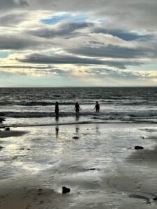 Three women entering the sea for a first cold plunge after an outdoor sauna session