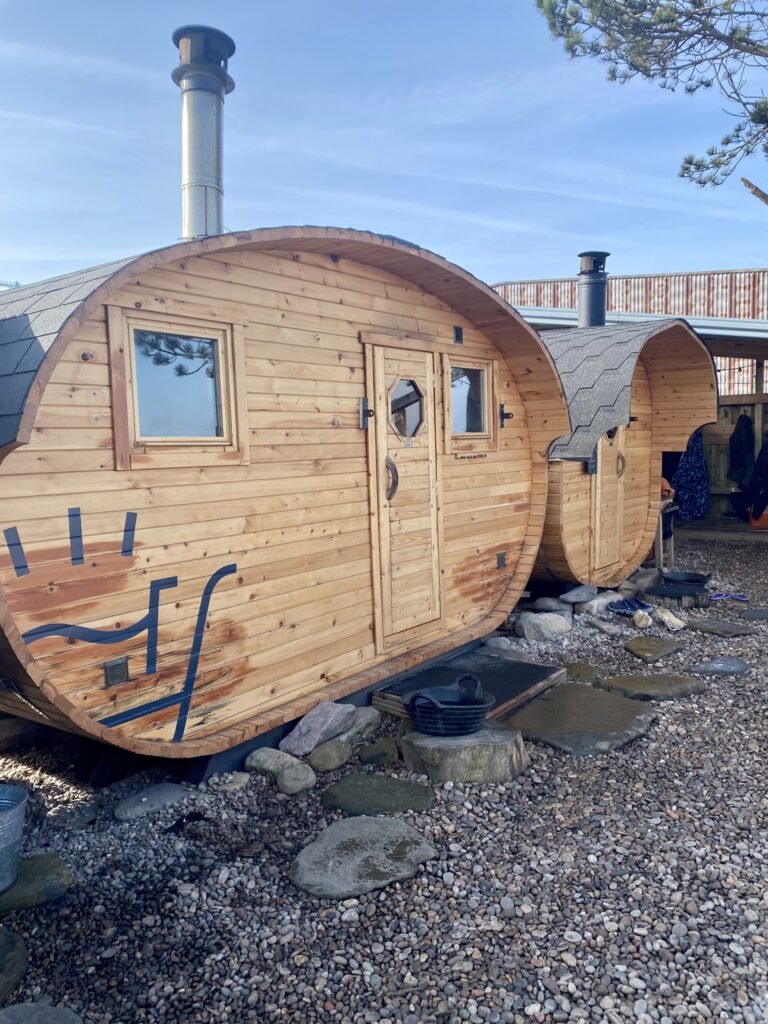 Two barrel saunas at Soul Water Sauna Granton on a pebble surface near the seafront