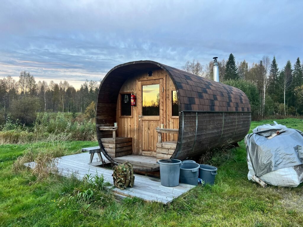 Barrel style wild sauna in a natural outdoor setting surrounded by grass and trees
