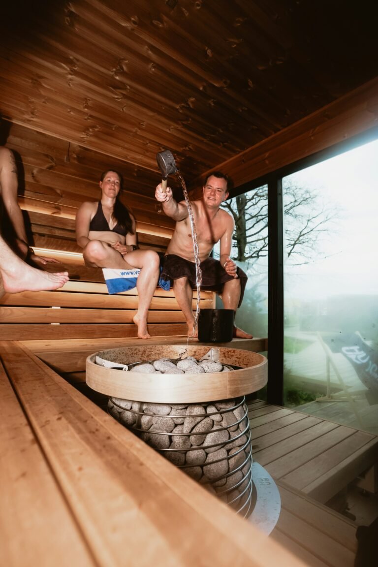 Person pouring water over hot stones in a wood fired wild sauna to create steam