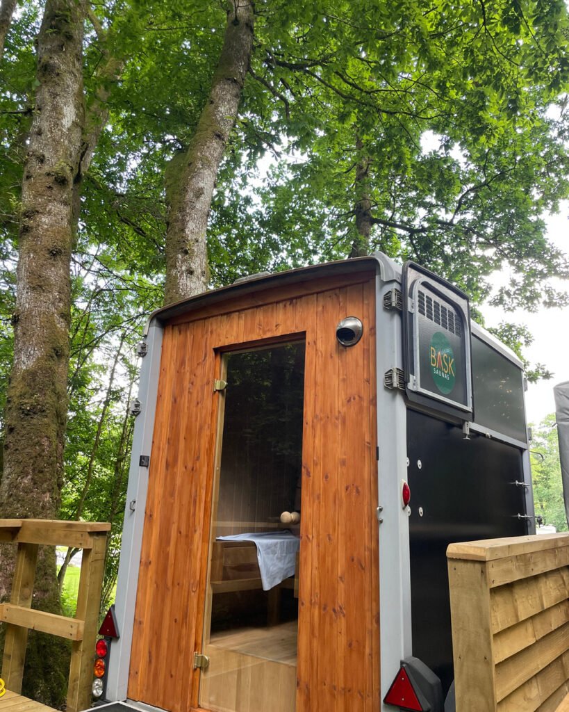 Wood-fired sauna exterior with wooden door in woodland setting