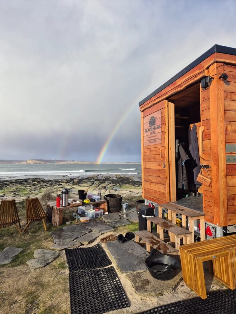 Mobile sauna overlooking Castletown Beach with rainbow over the sea in Caithness