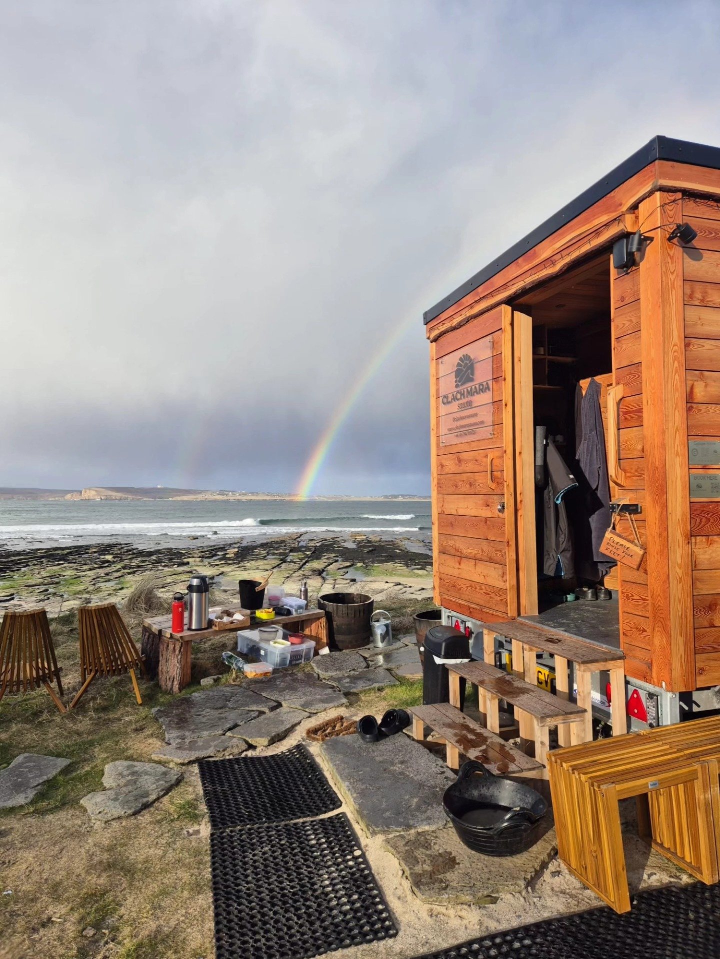 Mobile sauna overlooking Castletown Beach with rainbow over the sea in Caithness
