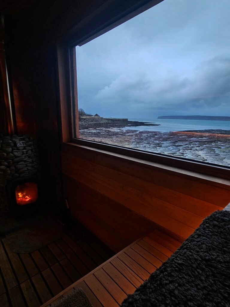 View from inside sauna looking out to rocky Caithness coastline with fire glowing