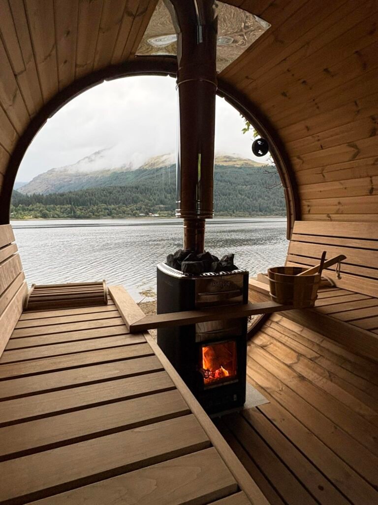 Interior of Eir Sauna’s wood-fired barrel sauna overlooking Loch Long through a circular window