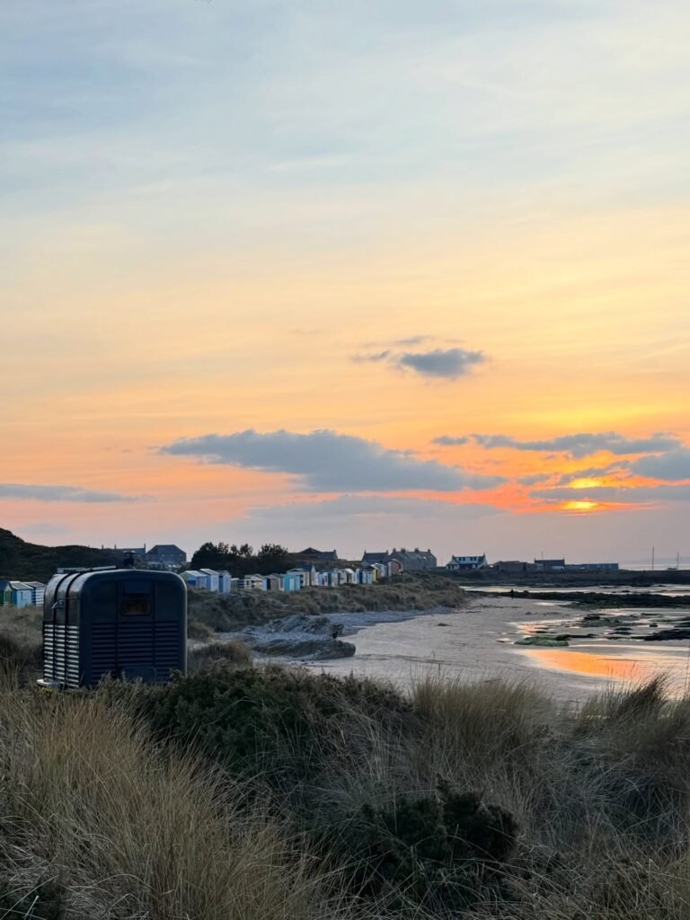 Fyrhus sauna in sand dunes with colourful beach huts at Hopeman East Beach during sunset