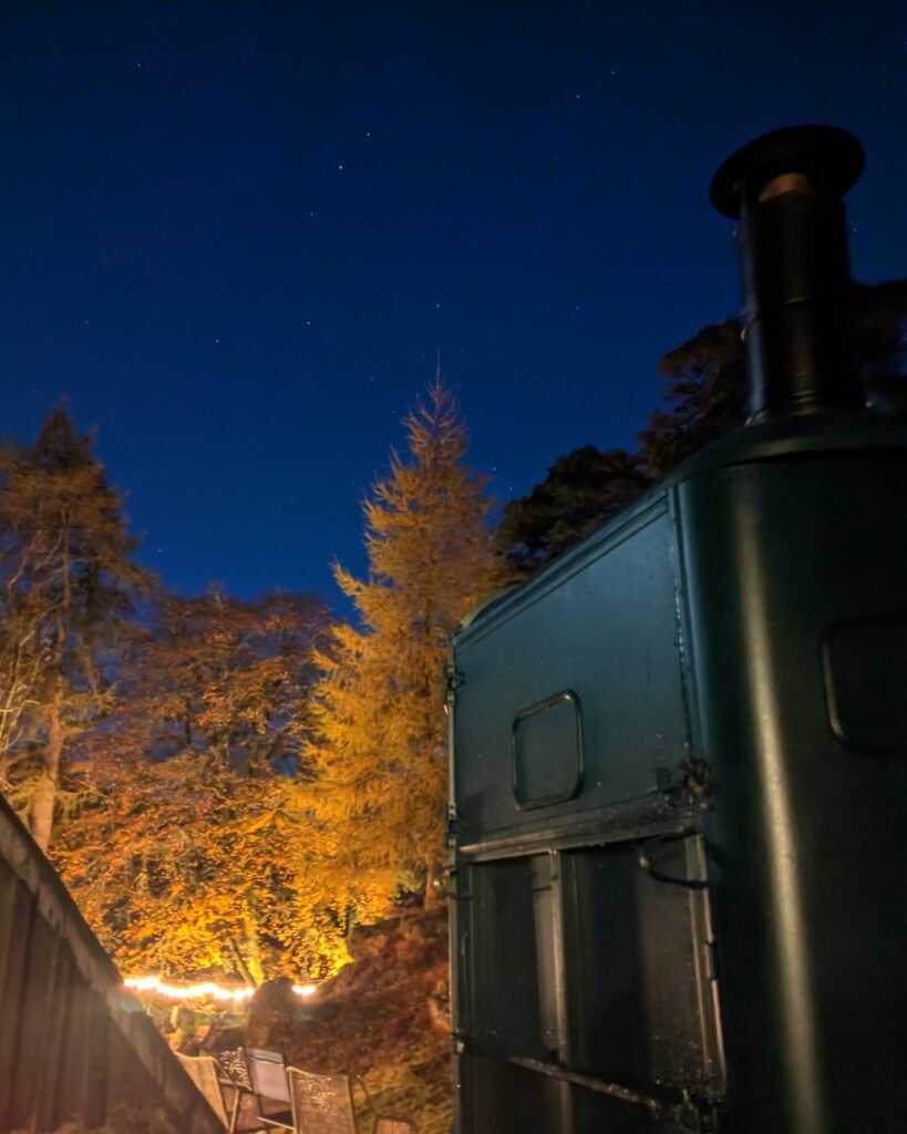 Wood-fired outdoor sauna lit at night under a starry sky in the Scottish Highlands