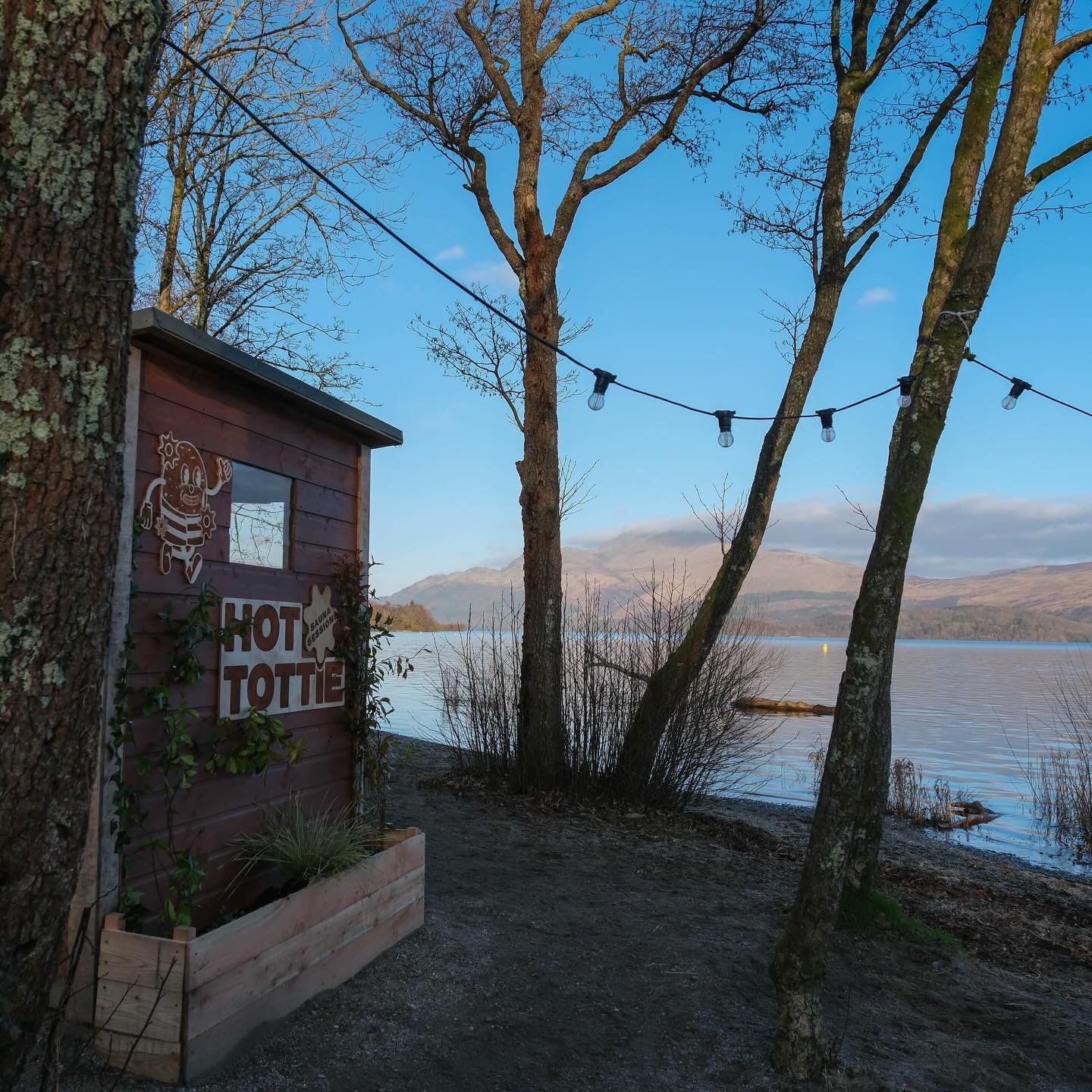 Wood-fired sauna at Hot Tottie in Luss overlooking Loch Lomond, framed by trees