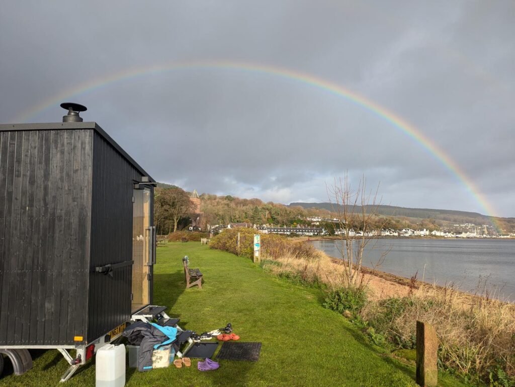 Mobile sauna overlooking the coast at Whiting Bay with rainbow over the water