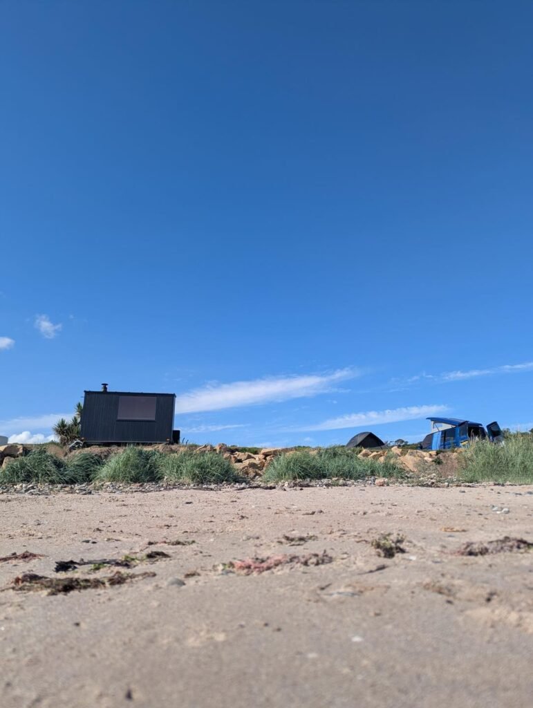 Black mobile sauna cabin set just above the beach on the Isle of Arran