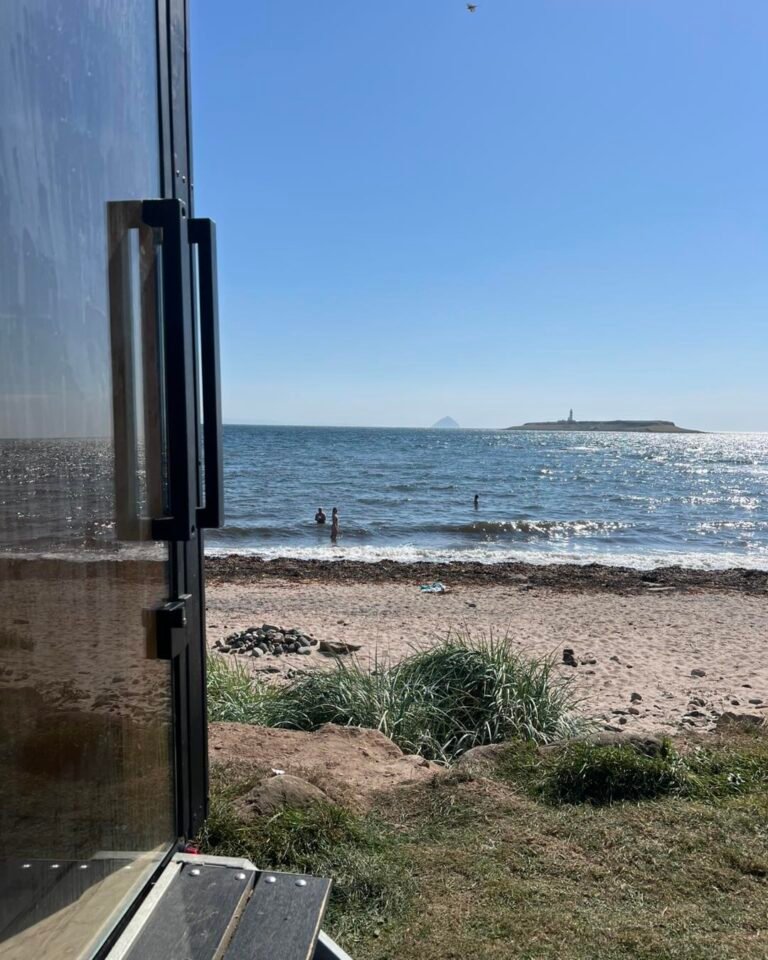 View from the sauna doorway across Whiting Bay with people sea swimming