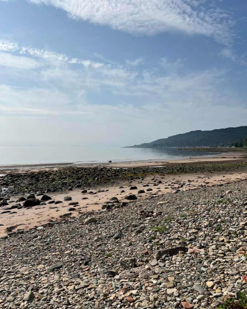 Wide view of Whiting Bay beach with rocky shoreline and calm sea on the Isle of Arran