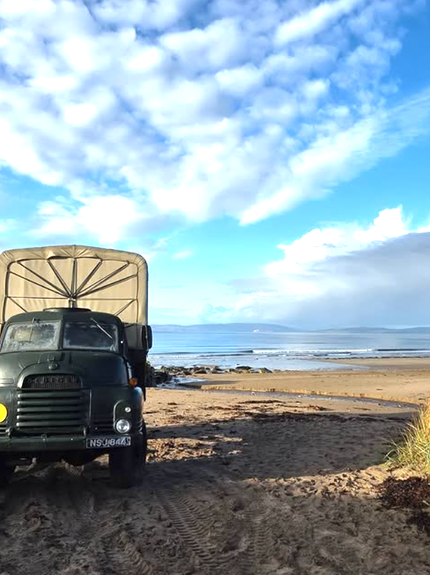 Converted army truck sauna on sandy beach overlooking the sea