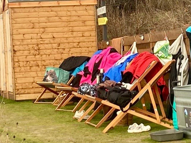 Changing robes, towels and bags left outside a coastal outdoor sauna in Scotland