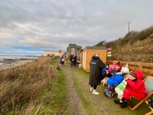 People relaxing beside a coastal outdoor sauna in Scotland
