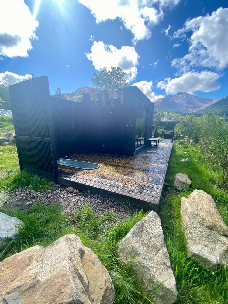 Exterior of Wilderness Sauna on the hillside at Woodlands Glencoe with mountains behind