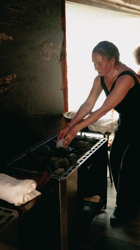 Aufguss Master placing ice ball on sauna stones at the 2026 UK Aufguss Championships at Galgorm Resort