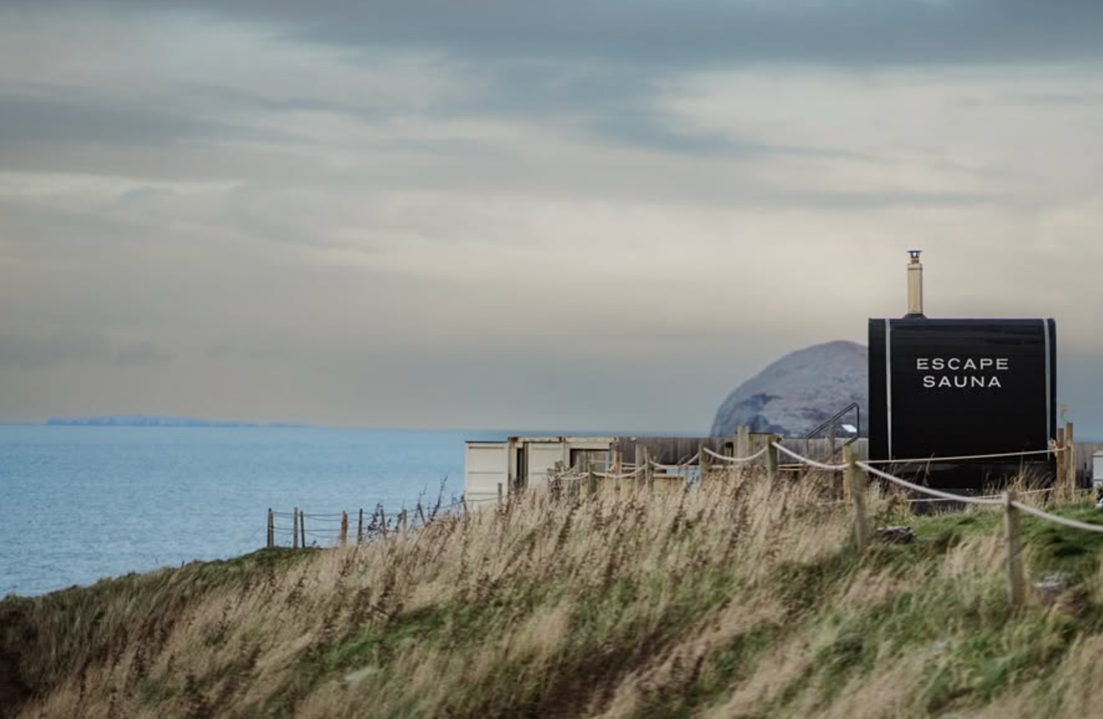 Escape Sauna North Berwick exterior at sunset with Bass Rock visible in the background