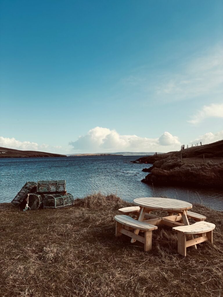 View across Ollaberry Bay from Nordic Glow Shetland Hot Hoose sauna with picnic bench and fishing net boxes