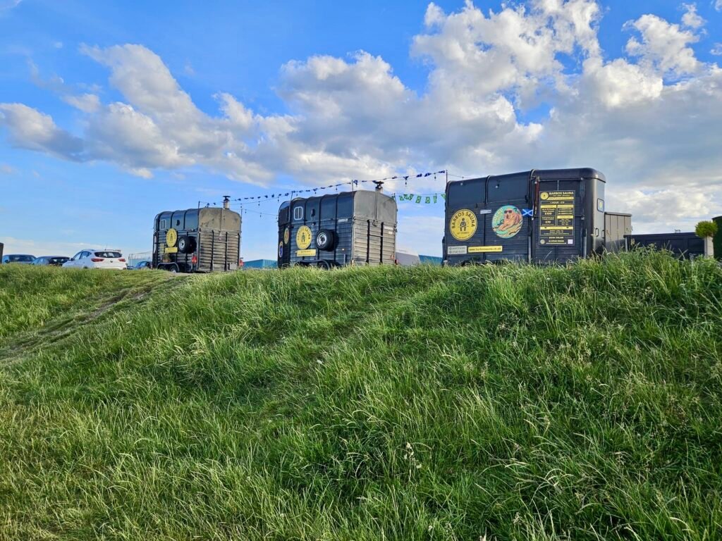 Barbossauna's converted horsebox saunas on Aberdeen beach, with pricing signage and bunting