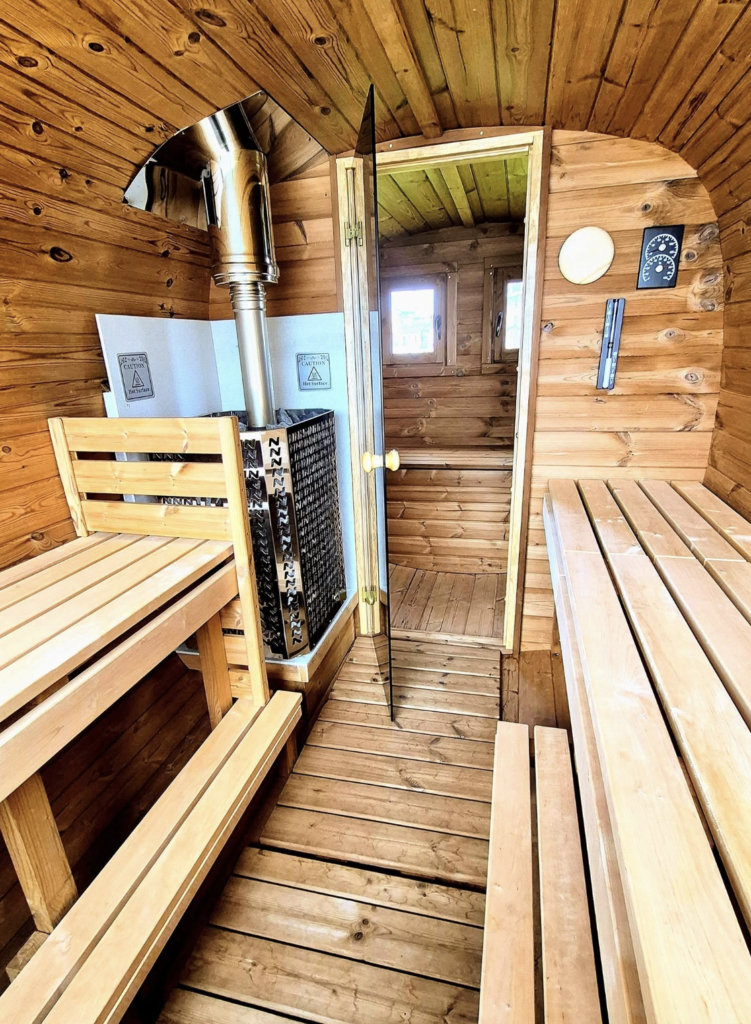 Orka Sauna, Burghead: interior view of the benches and wood stove inside the barrel sauna