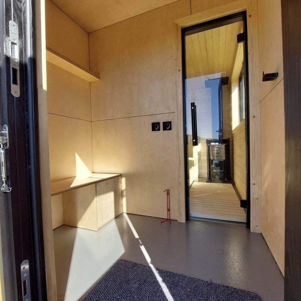 Stravaig Sauna Crathie interior showing the lit Harvia wood-fired stove and birch whisks