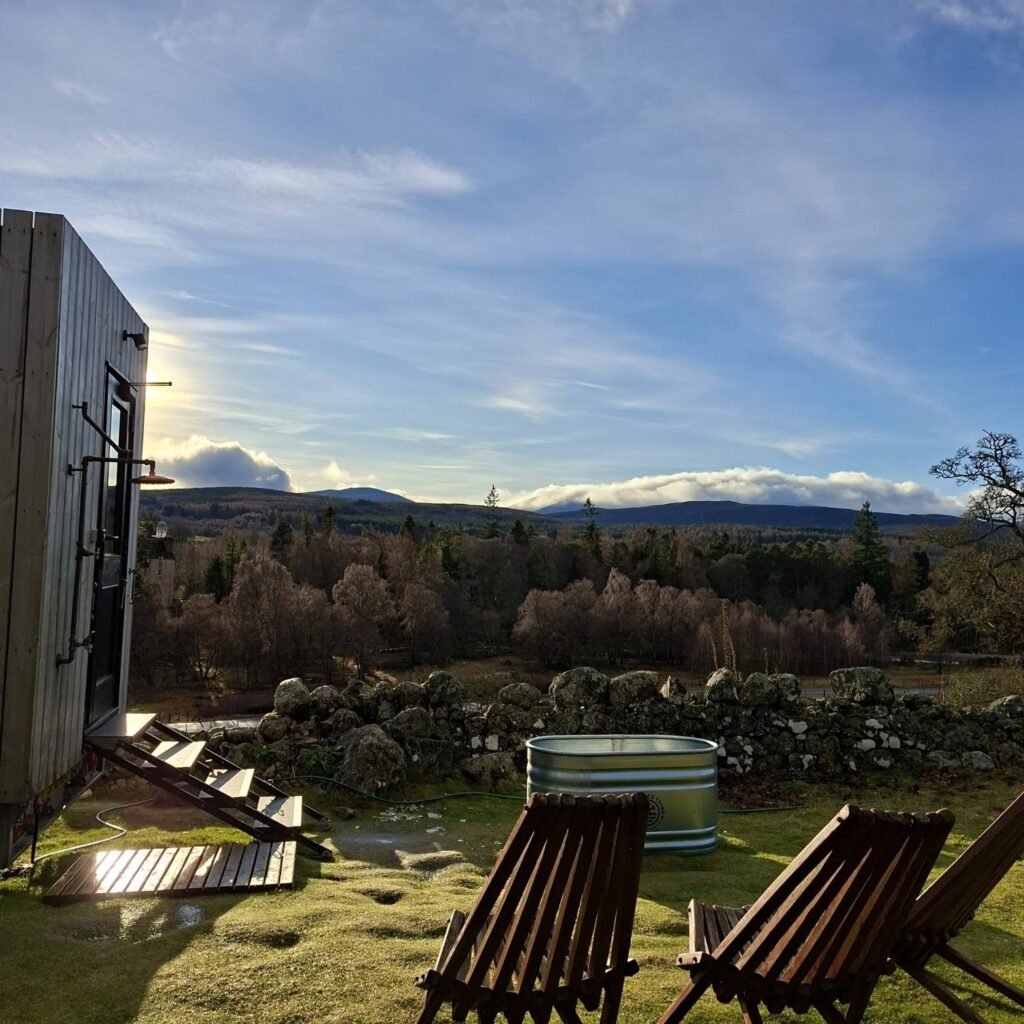 Stravaig Sauna Crathie exterior at golden hour with deck chairs and dry stone wall