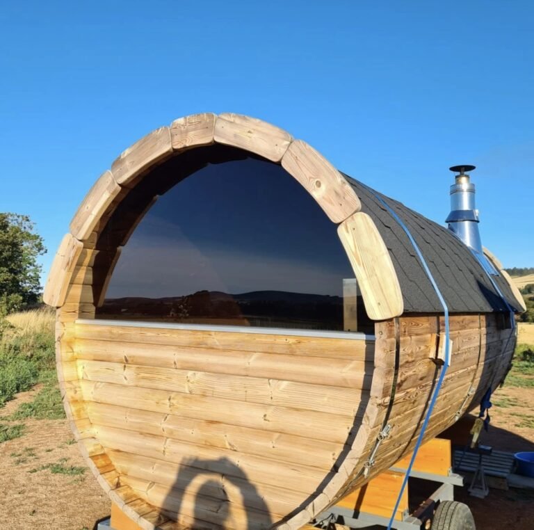 The Little Sauna Keig barrel sauna exterior with dark window reflecting blue sky