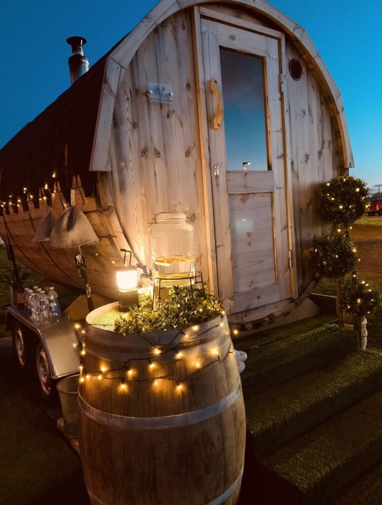 The Sauna Hoose Fraserburgh whisky barrel table lit with fairy lights at dusk