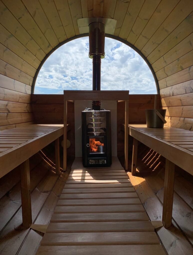 The Sauna Hoose Fraserburgh interior with wood-fired stove lit and arched window framing the sky