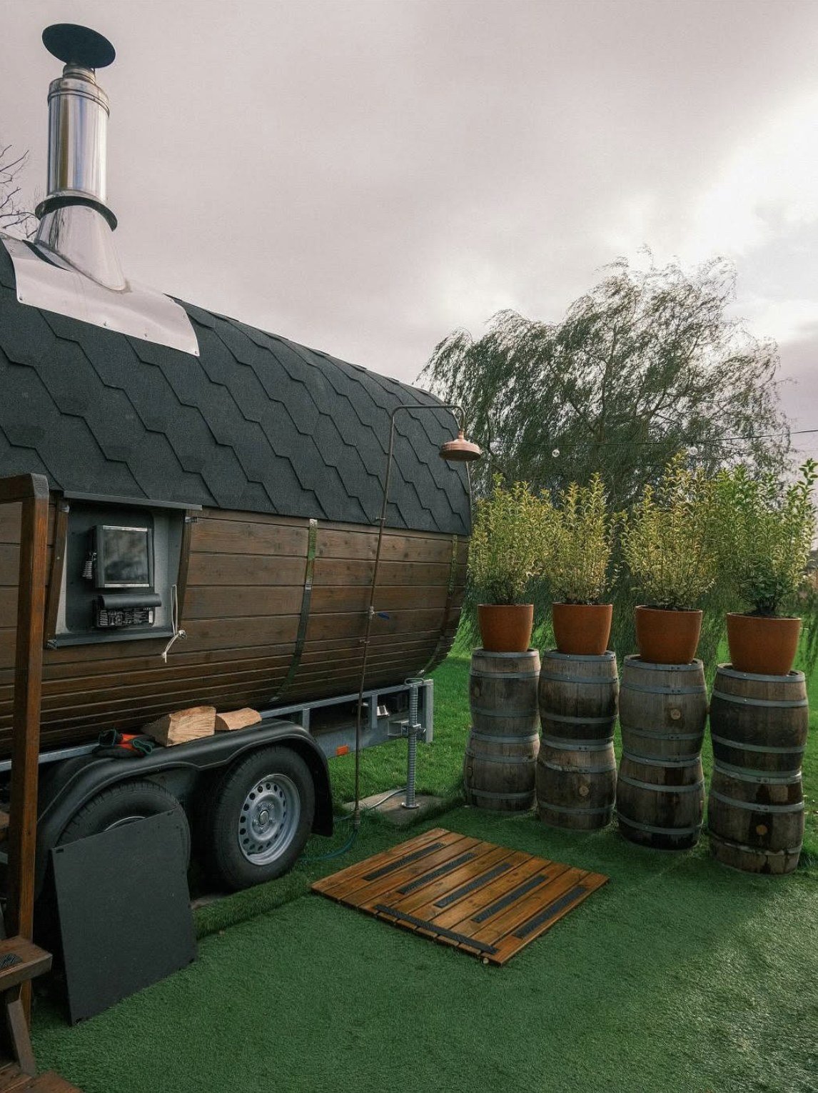 The Wild Heat Glasgow barrel sauna exterior with copper shower and barrel planters