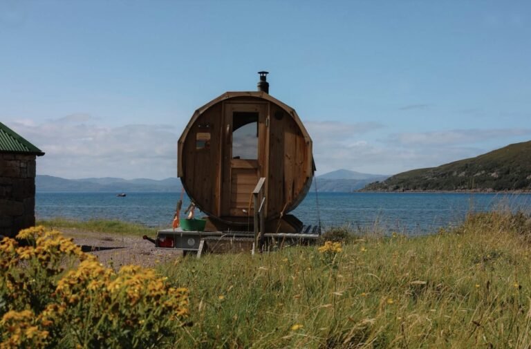 Applecross Sauna Wester Ross wood-fired barrel sauna on a trailer beside Applecross Bay with yellow ragwort in the foreground