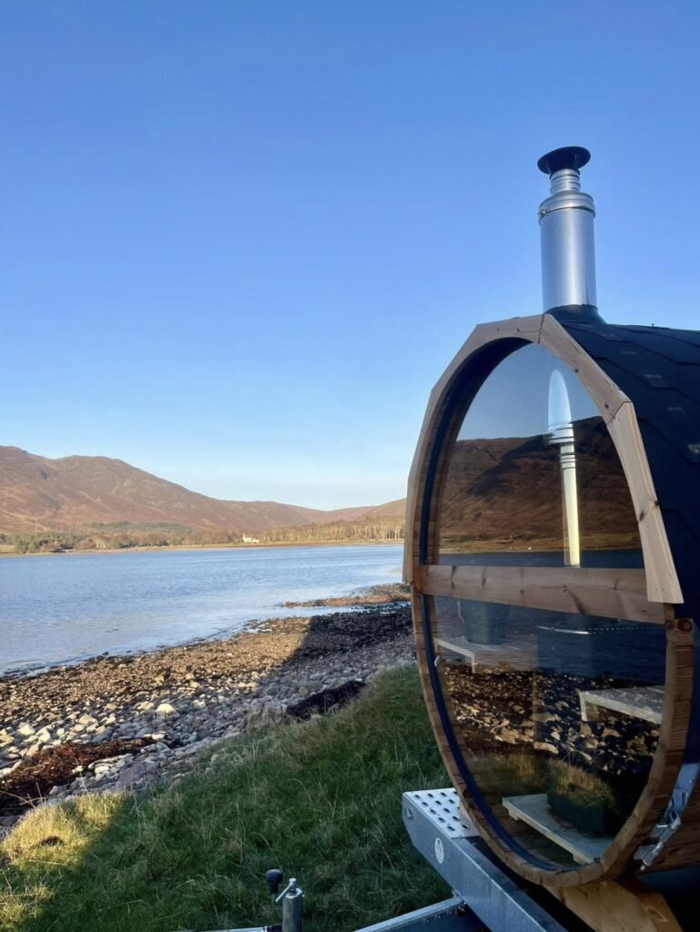 Applecross Sauna Wester Ross glass-ended barrel sauna and flue beside the shore with hills across the bay