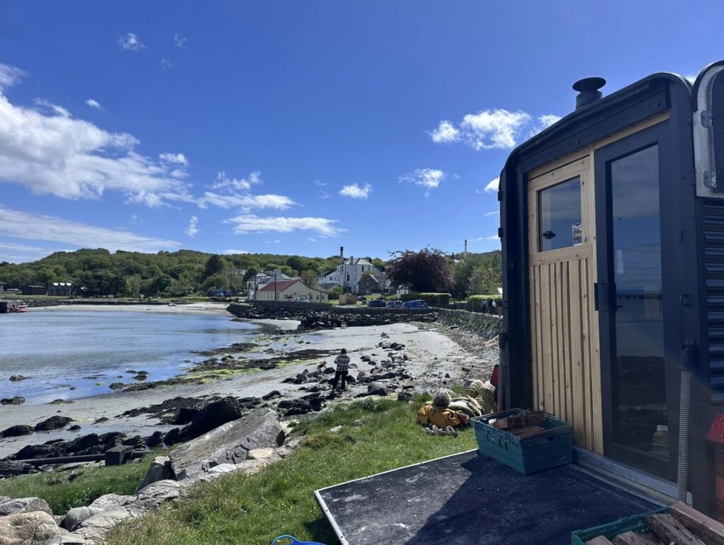 Bothan Jura Wild Sauna Isle of Jura sauna door and wood store looking along the bay to the village