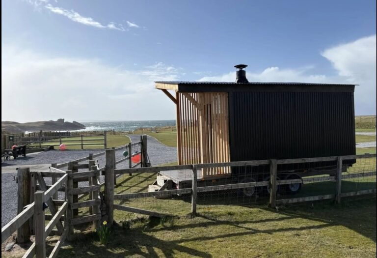 Loyly Sauna Clachtoll black timber and corrugated sauna cabin on a trailer beside the coast with the sea behind